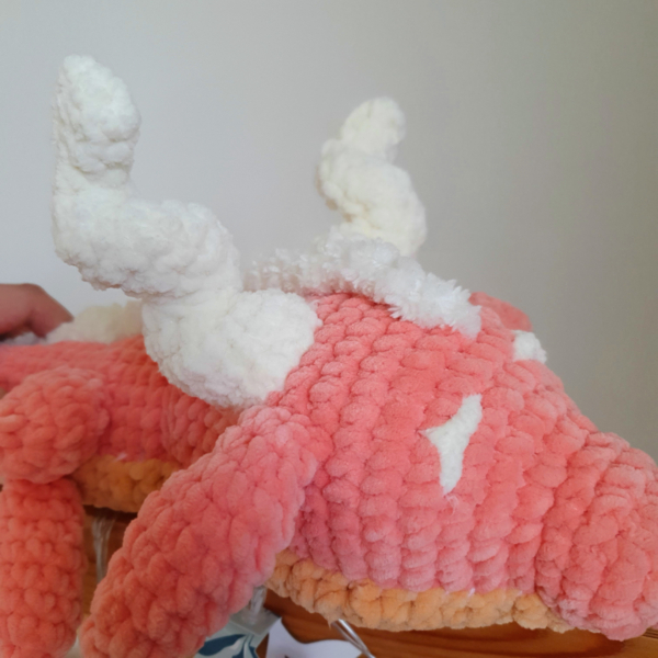 Gros plan sur la tête du dragon corail en laine fait main – peluche artisanale Les Doudous de Woolfy