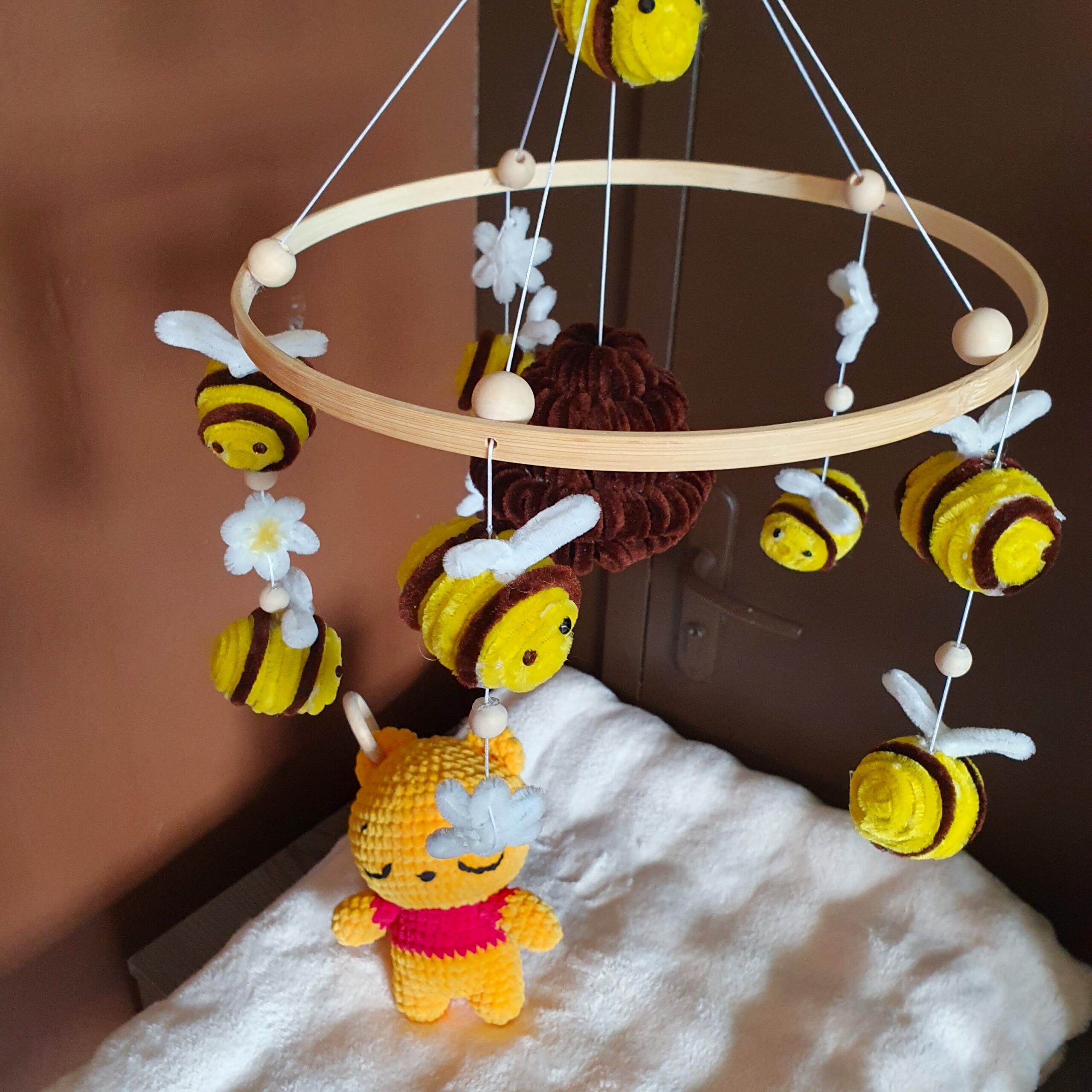 Le mobile Winnie sans ca peluche qui tourne au dessus de la table a langer ou est disposé la peluche Winnie.