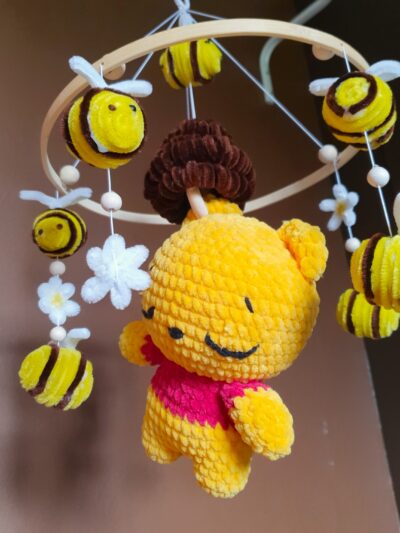 le mobile winnie sous un nouvel angle avec ca peluche centrale inspirer de winnie l'ourson entouré de ces abeille et ces fleurs qui tourne autour d'elle.