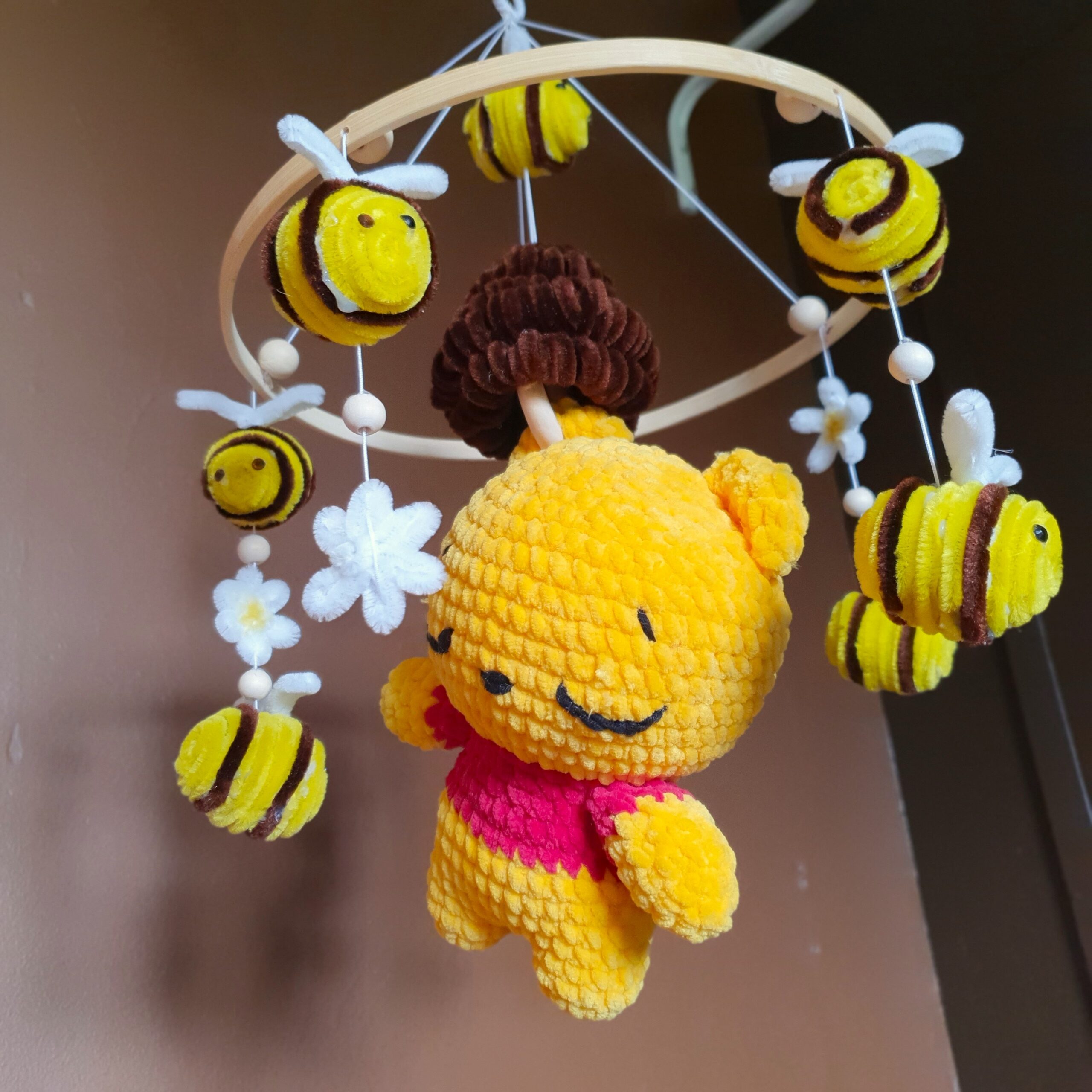 le mobile winnie sous un nouvel angle avec ca peluche centrale inspirer de winnie l'ourson entouré de ces abeille et ces fleurs qui tourne autour d'elle.